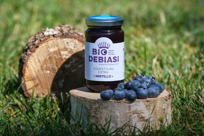 vasetto di confettura extra di mirtillo biologico biodebiasi in vetro in ambientazione all'aperto